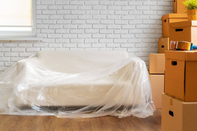 Sillón blanco con un plástico transárente encima y cajas de cartón apiladas en una sala de estar minimalista Bodega Guadalajara