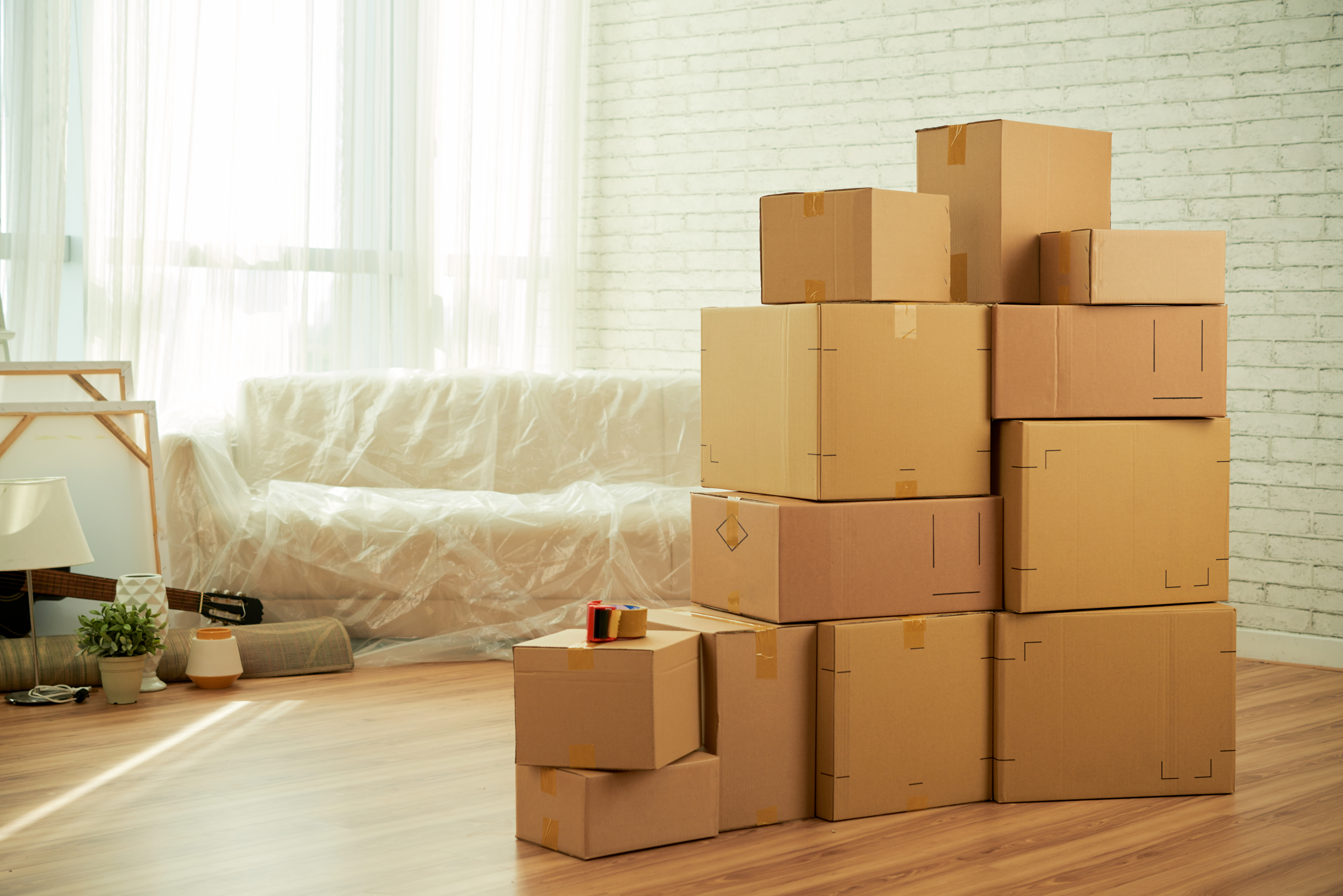 Sala de estar minimalista con un sillón blanco con plástico transparente y cajas apiladas en primer plano Bodega Guadalajara