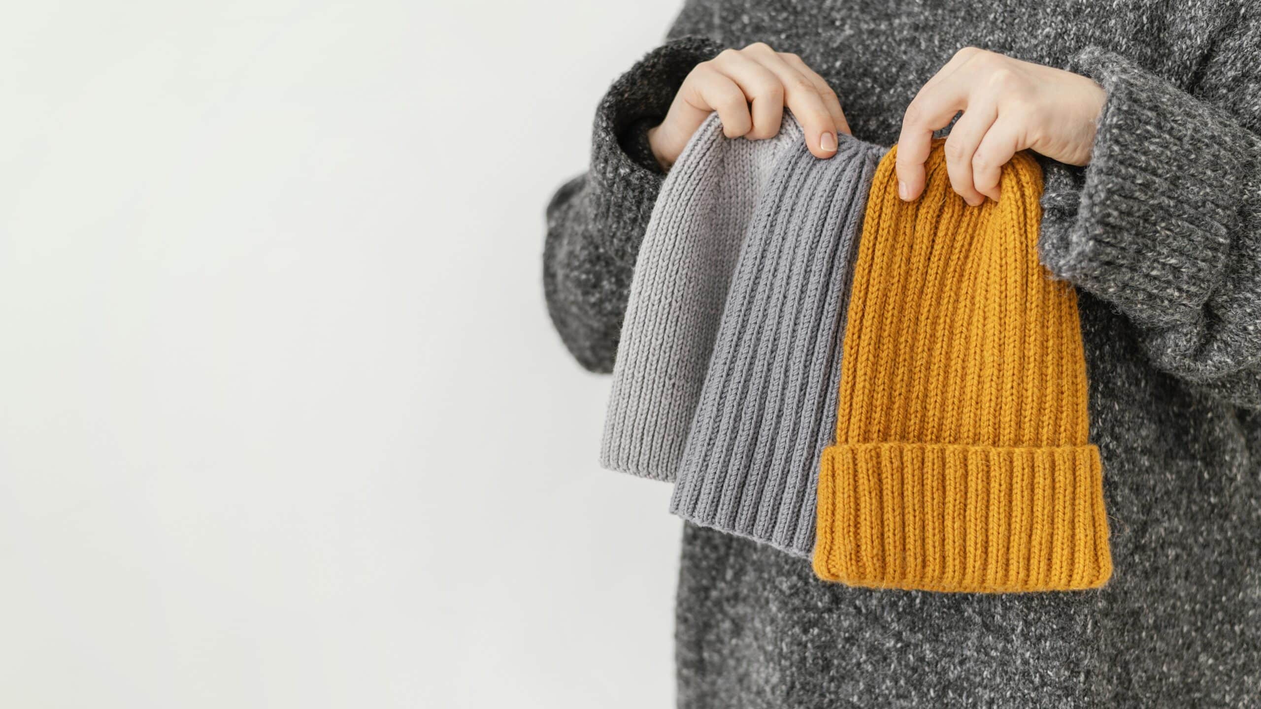 close-up-hand-holding-different-knitted-hats